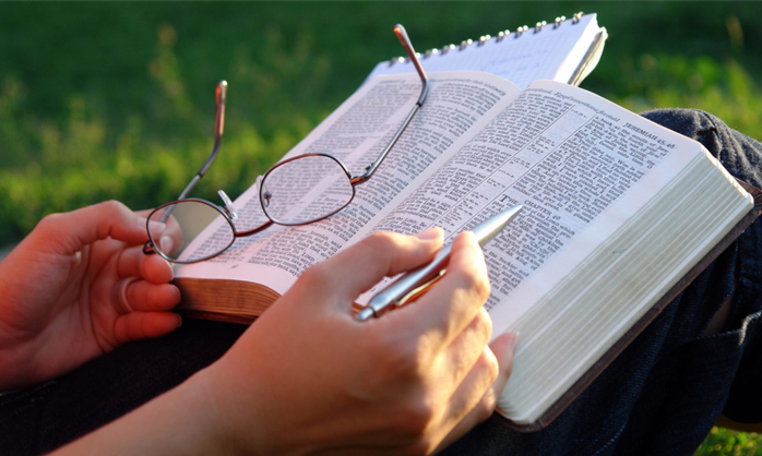 St. John's United Church | A person reading a bible with glasses and a pen.