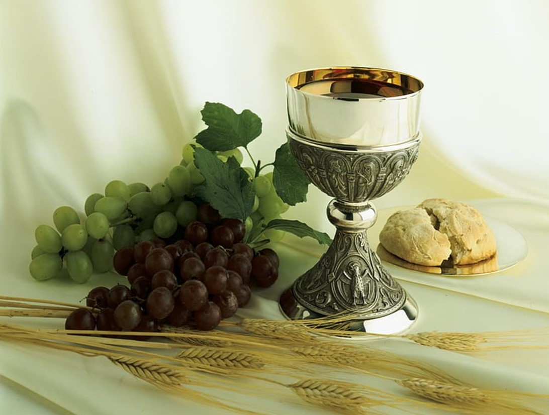 St. John's United Church | An ornate chalice with wine, surrounded by grapes, bread, and wheat stalks, arranged as a still life.