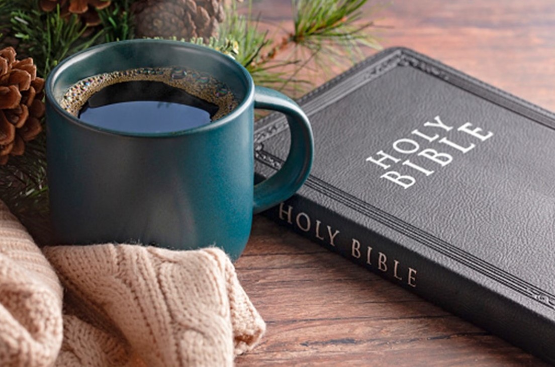 St. John's United Church | A blue mug of coffee, a knitted sweater, and a Holy Bible on a wooden table with pinecone decorations in the background.