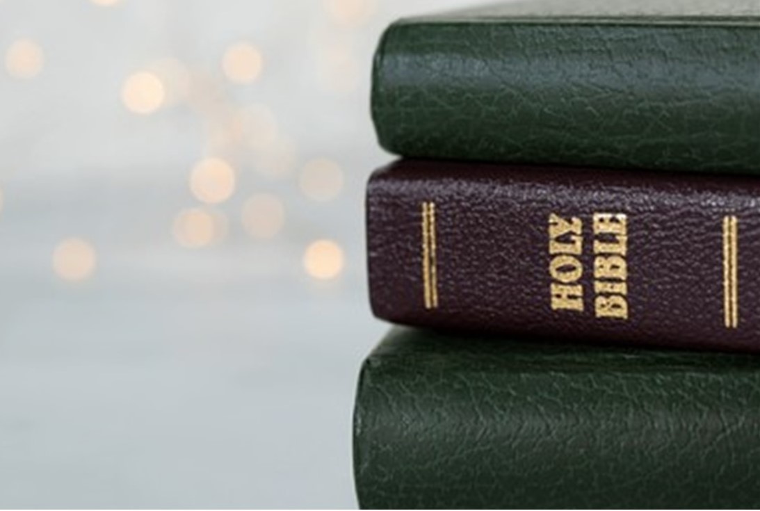 St. John's United Church | Stack of two green books with gold detailing, the top one labeled "Holy Bible," set against a blurred light background.