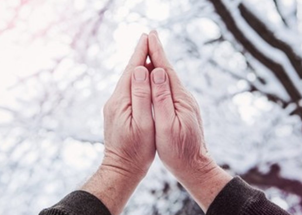 St. John's United Church | Hands held together in a prayer position against a blurred snowy background.